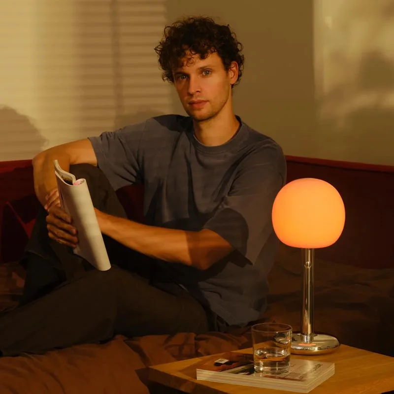 GRAU Fire Table Tischleuchte Poliert am Tisch mit lesender Person